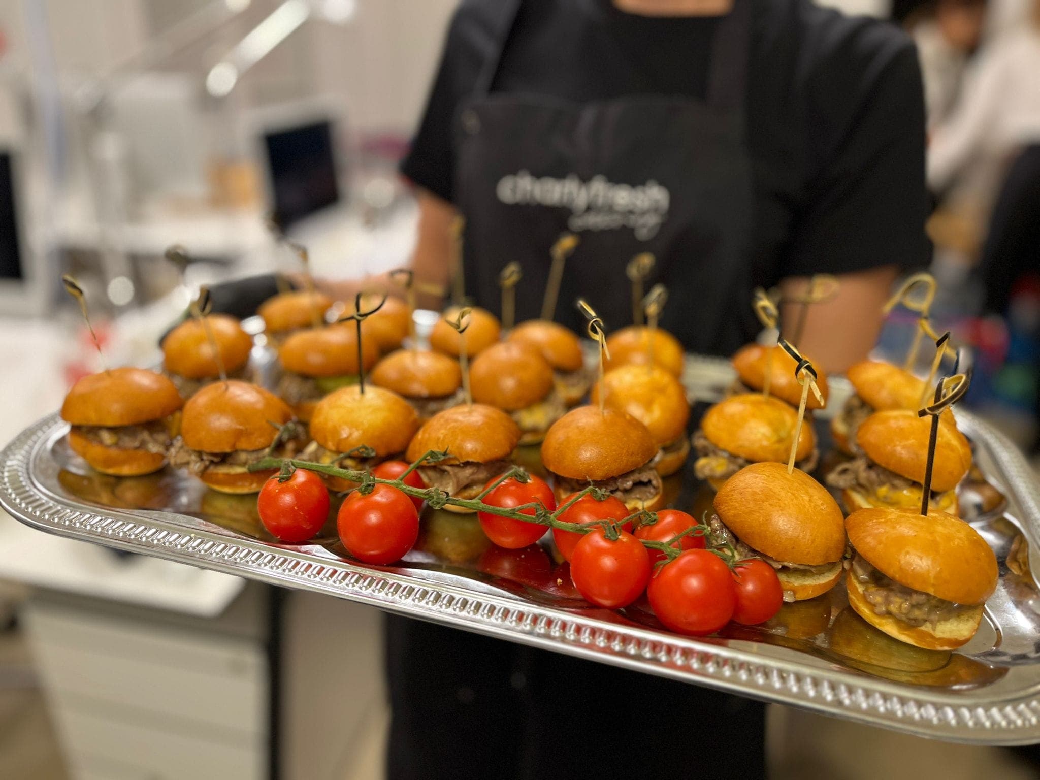 charlyfresh Catering — Mini-Burger-Platte mit Cocktailtomaten, serviert vom Team